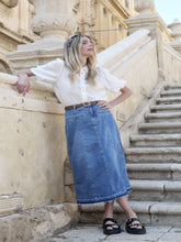 A lady wears a shirt and a blue skirt.